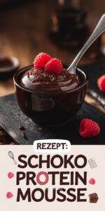 Schokoladen-Protein-Mousse in schwarzem Keramikschälchen auf Walnussholz – luftige dunkelbraune Mousse mit geraspelter Schokolade und roten Himbeeren Löffel zeigt die luftige Textur